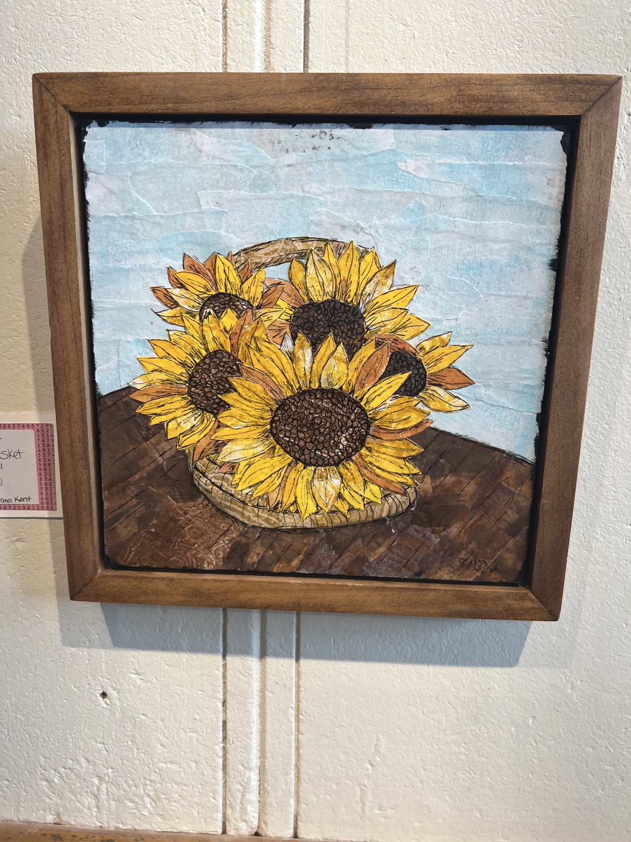 A sunflower still life built from torn and layered paper, one of the collage pieces on display.