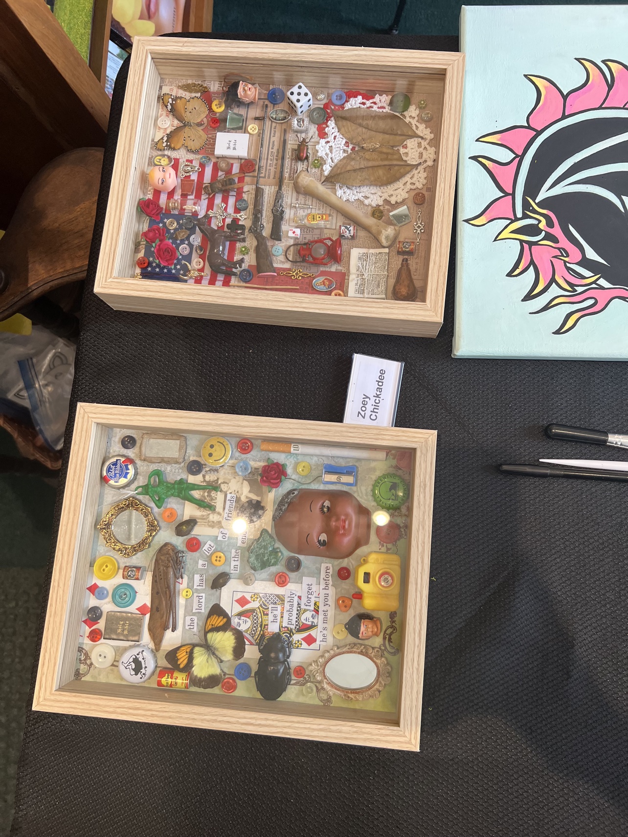 Shadow boxes by Zoey Chickadee, assembled from buttons, butterflies, doll parts and whatever else fits.