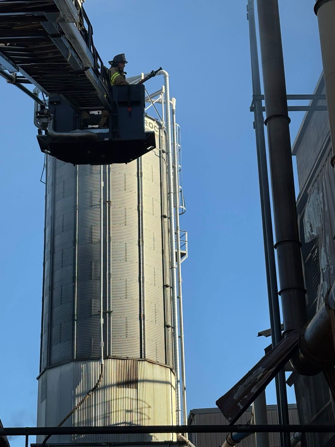 A firefighter in an aerial bucket works beside the plant silo.