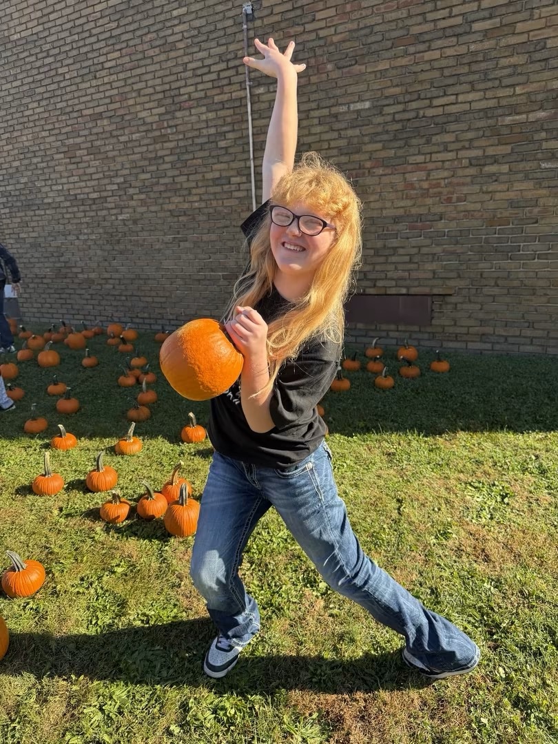 A student dancing while holding a pumpkin