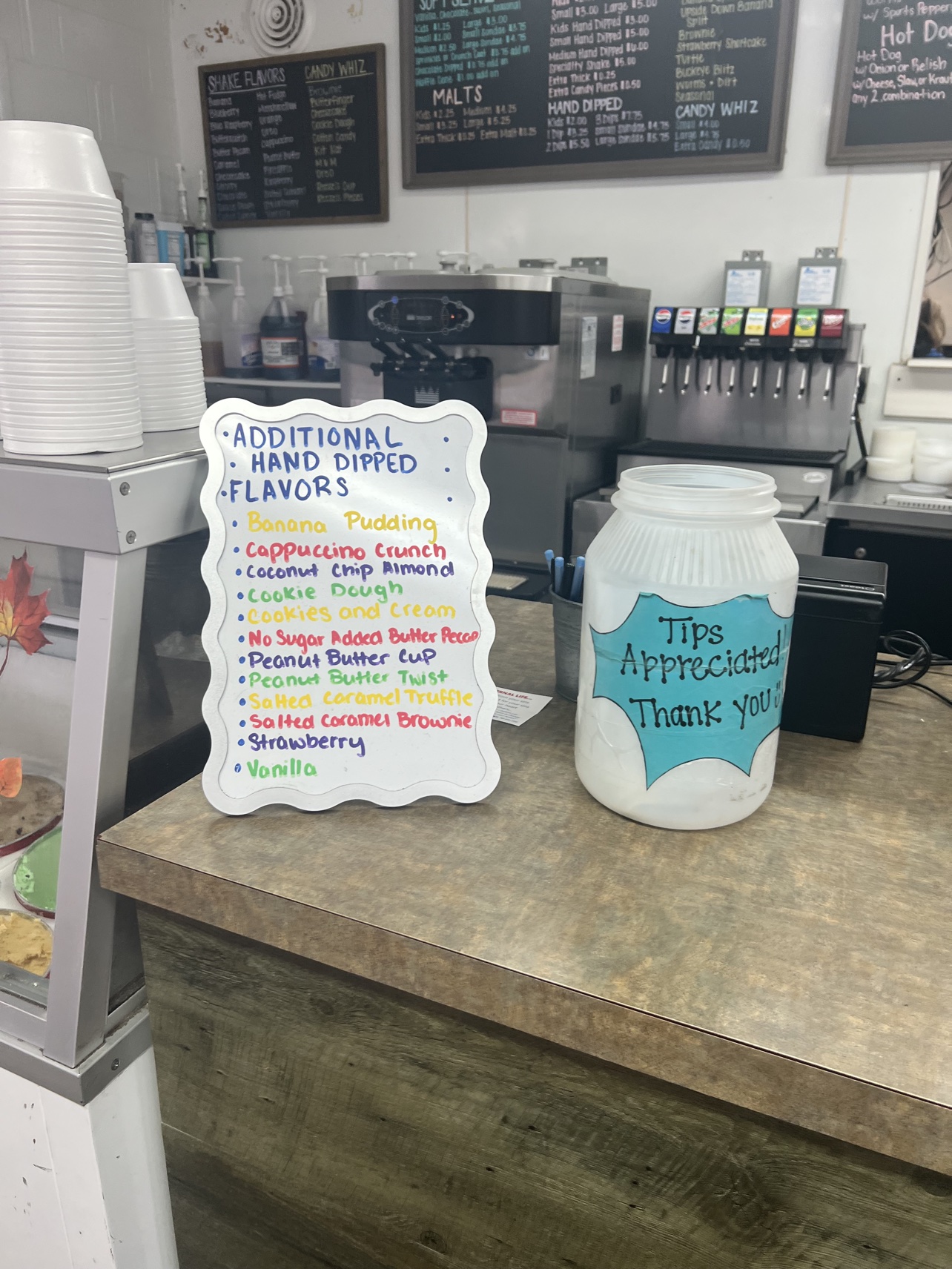 Handwritten list of hand-dipped ice cream flavors and tip jar at Tony's Coney's