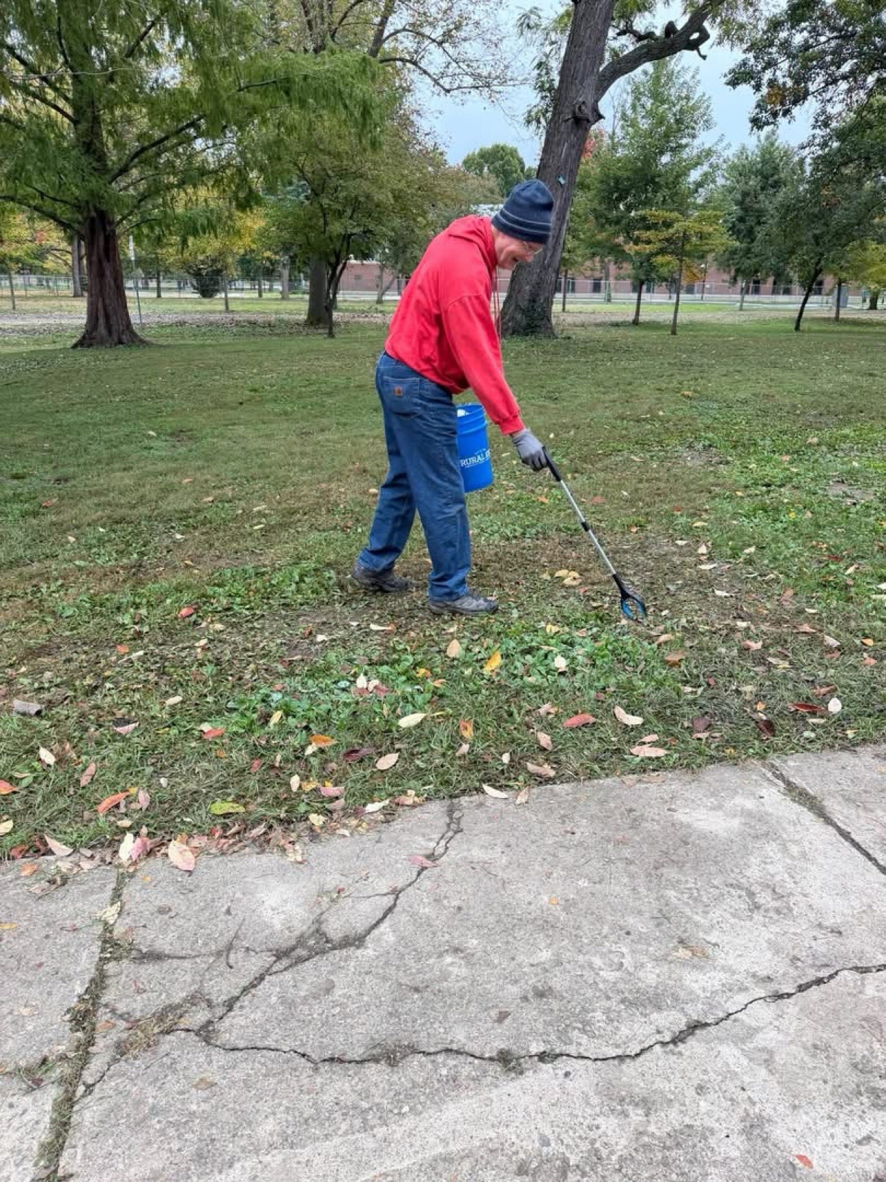 A volunteer picks up litter at Yoctangee Park